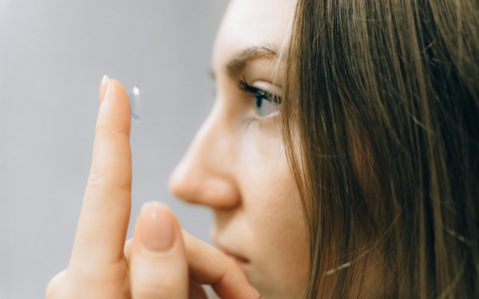 Femme posant une lentille de contact sur le bout de son doigt